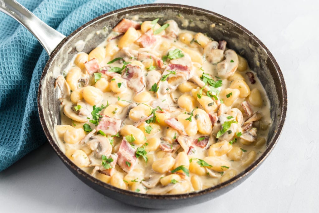 Gnocchi with mushrooms and bacon in a skillet.
