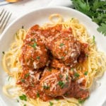A pile of spaghetti in a bowl with 3 meatballs and tomato sauce