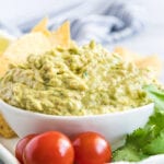 Guacamole in a white bowl with cherry tomatoes