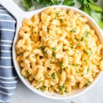 Mac and cheese in a white bowl with parsley and a blue linen