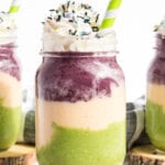 Smoothie layered in green, orange and purple with whip cream.