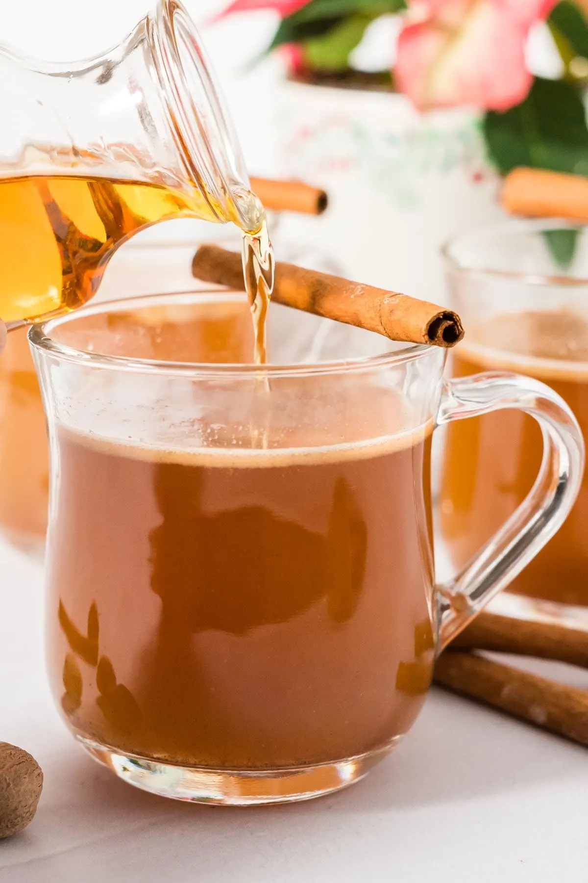 Rum being poured into a mug of hot buttered rum mix.