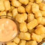 Tater tots in a bowl with spicy mayo dip.