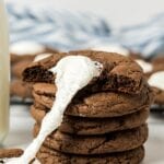 Hot chocolate cookie broken in half with a melted marshmallow stretching between.