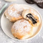 Three fried Oreos on a plate with a bite out of one.