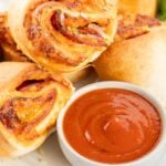 Air fried pizza rolls on a platter with dipping sauce.