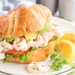 Shrimp on a croissant with pea shoots, tomato and avocado slices.