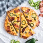 Flatbread baked with cheese, bacon and jalapeños sliced into four wedges.
