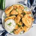 Jalapeno poppers on a plate with a dish of ranch dip.