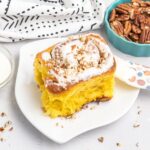 Cinnamon roll with cream cheese icing and chopped pecans.