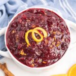 Cranberry sauce garnished with orange zest in a white bowl.