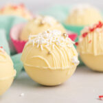 White chocolate cocoa bomb with white and gold sprinkles.