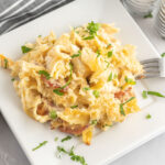 A portion of chicken noodle casserole on a plate garnished with fresh parsley.