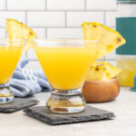 Pineapple martini in a stemless martini glass garnished with a pineapple wedge.