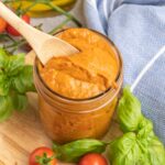 Pizza sauce in a small mason jar with a wooden spoon.