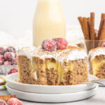 Slice of spice cake filled with pudding, topped with whipped topping and sugared cranberries.