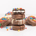 A stack of chocolate covered Oreos with a bite taken from the top cookie.