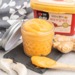 A small jar of prepared mayonnaise with a container of gochujang paste in the background.