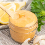 Harissa flavoured mayo in a small mason jar with a wooden spoon.