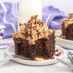 A slice of chocolate cake with chocolate whipped topping, drizzled with caramel and chocolate sauce and chopped pecans.