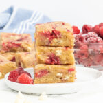 A stack of raspberry white chocolate blondies on a small plate.
