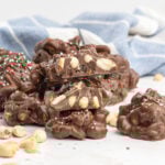 A stack of chocolate peanut clusters decorated with red and green sprinkles.