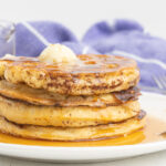 A stack of four French toast waffles with butter and syrup.
