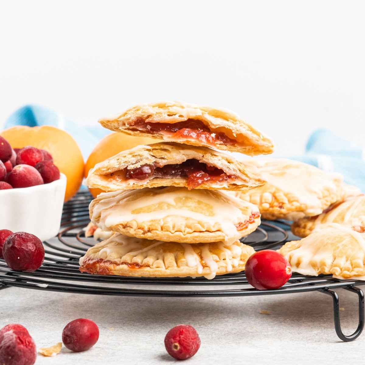 Round cranberry handpies in a stack with one broke open showing cranberry sauce inside.