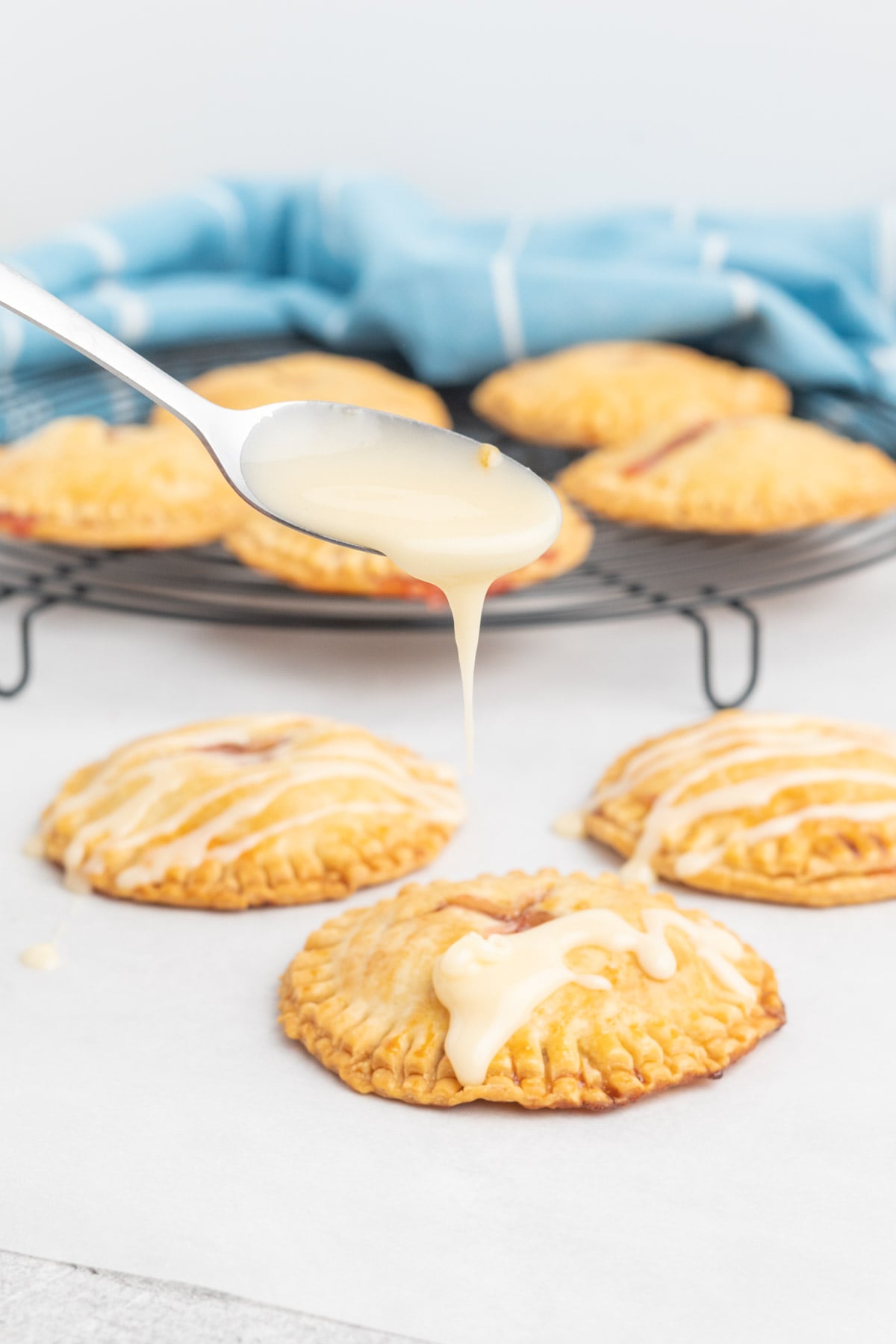 Icing drizzle being spooned over a hand pie.