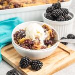 A bowl of blackberry dump cake topped with vanilla ice cream.