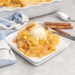 Apple cobbler on a small plate with a scoop of ice cream.