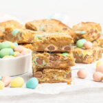 A stack of mini egg blondies and a small bowl of mini eggs.
