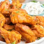 Hot wings on a plate with a dish of blue cheese dip.