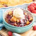 Berry cobbler in a small bowl topped with vanilla ice cream.