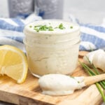A small jar of mayonnaise with chives and a small spoon.