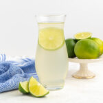 A bottle of lime syrup with a lime slice inside.