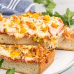 French bread pizza with peppers and ham on a plate.