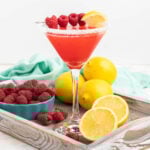 Raspberry martini in a martini glass garnished with a sugared rim, raspberries and lemon wedge.