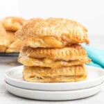 Three apple turnovers with cinnamon sugar on a plate.