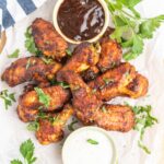 A platter of wings with ranch and bbq dip.