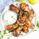Ranch chicken wings on a plate with a dish of ranch dip.