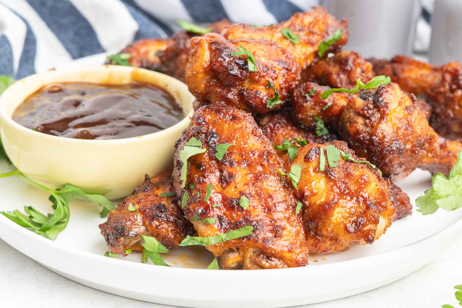 BBQ chicken wings with a dish of BBQ sauce.
