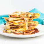 A stack of quesadilla wedges filled with bacon and cheese.