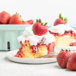 A slice of yellow cake with strawberry sauce and whipped topping.