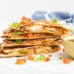 A stack of quesadilla wedges filled with chicken, cheese, BBQ sauce, and bell peppers.