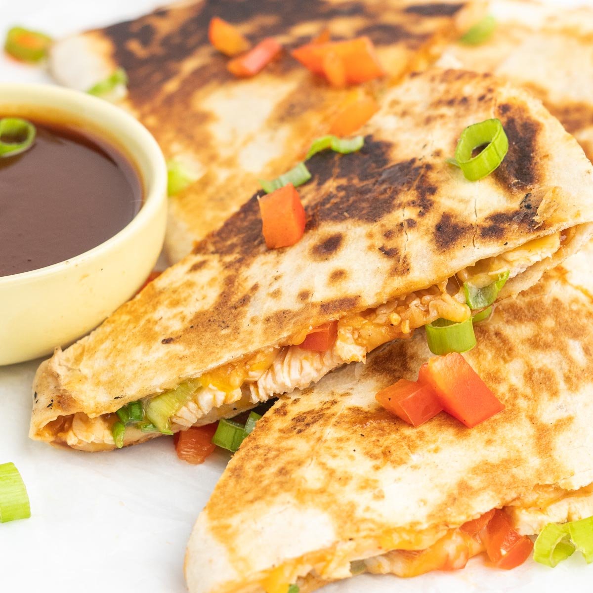 A stack of quesadilla wedges filled with chicken, cheese, BBQ sauce, and bell peppers.