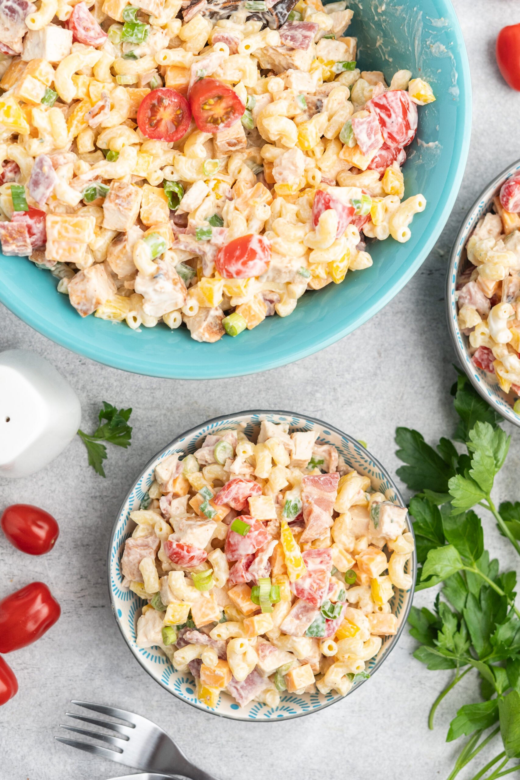 A serving bowl of pasta salad and two small individual portions in bowls. 