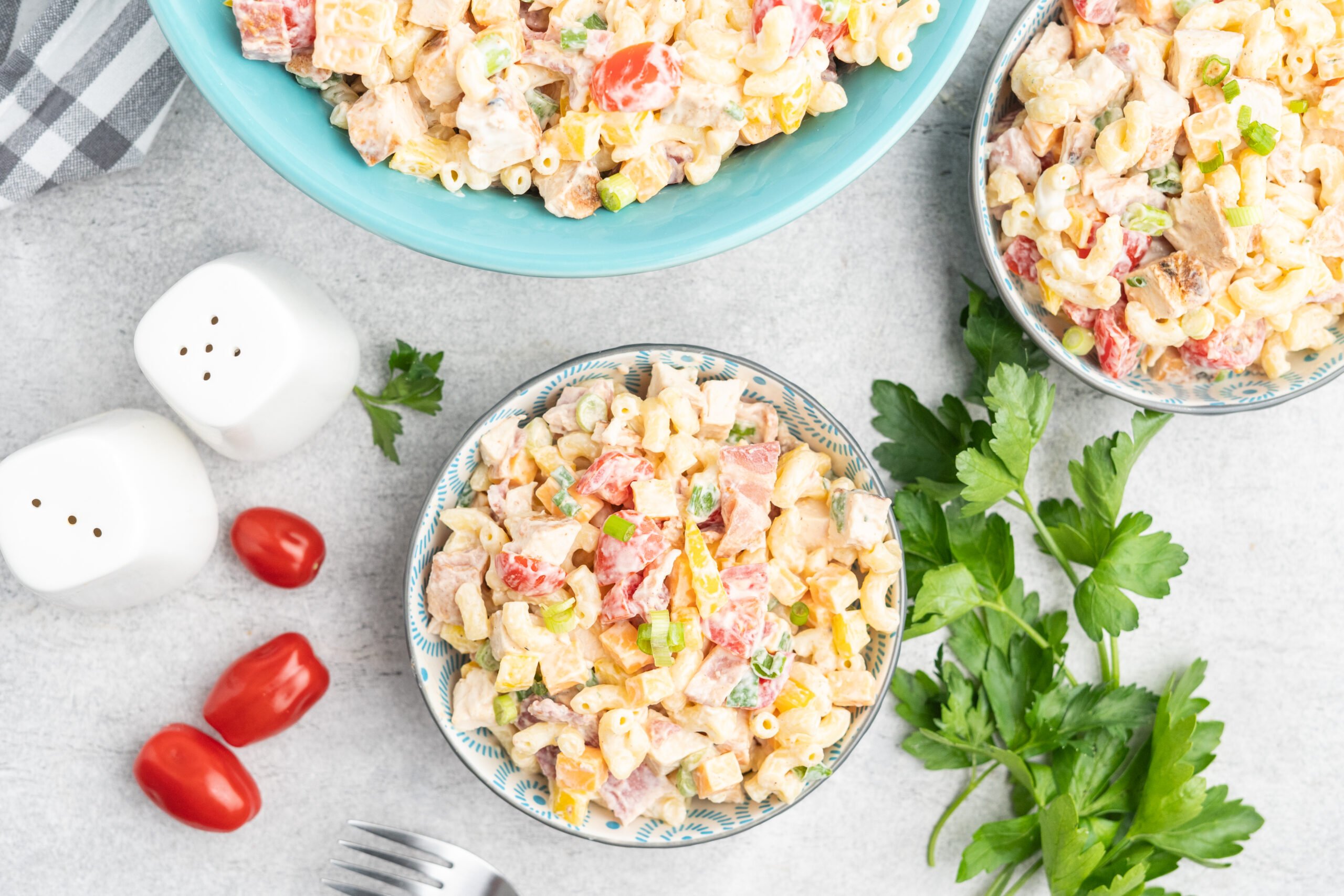 A serving bowl of pasta salad and two small individual portions in bowls.