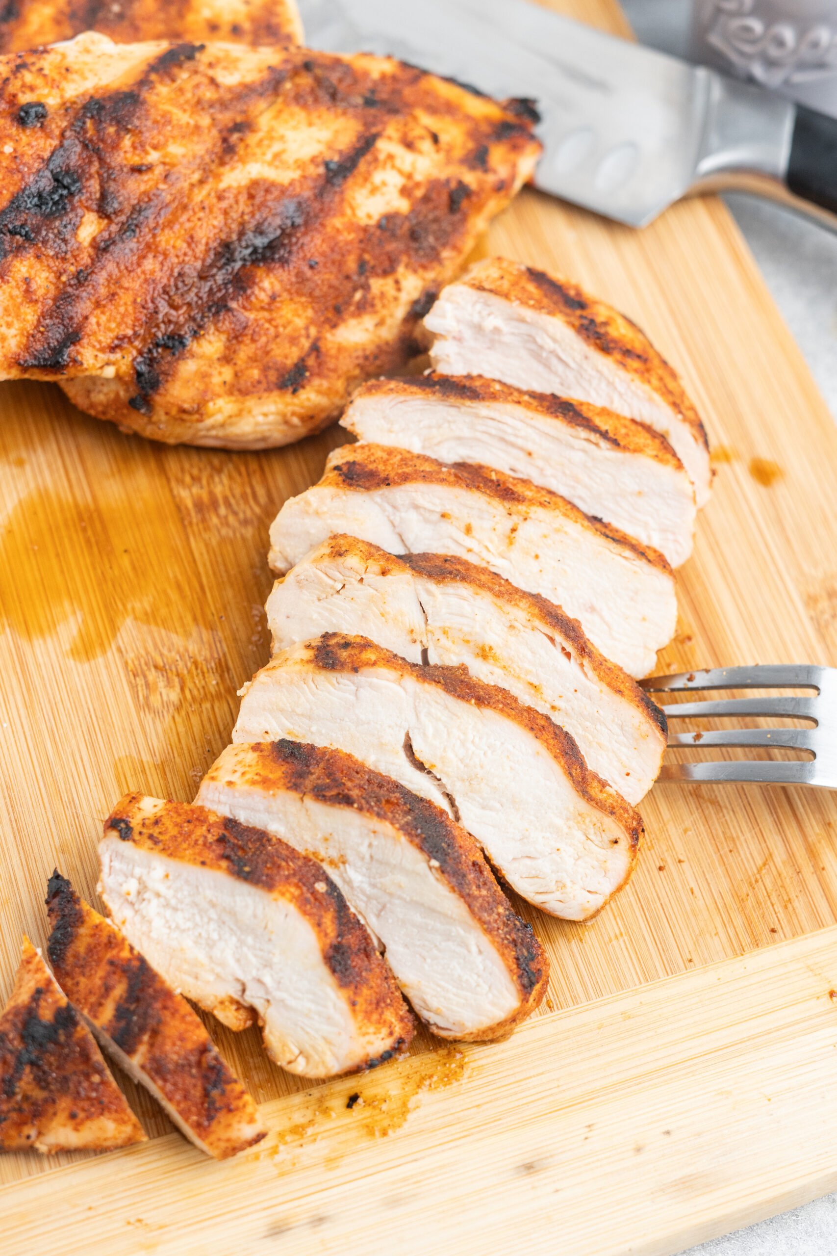 Sliced grilled chicken breast on a cutting board. 