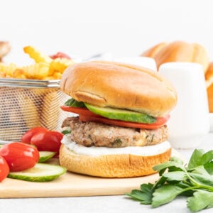 Turkey burger with cucumber and tomato on a brioche bun.
